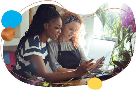 Two business woman reviewing merchant services on tablet.