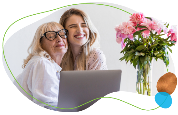 happy grandmother hugging granddaughter on a laptop